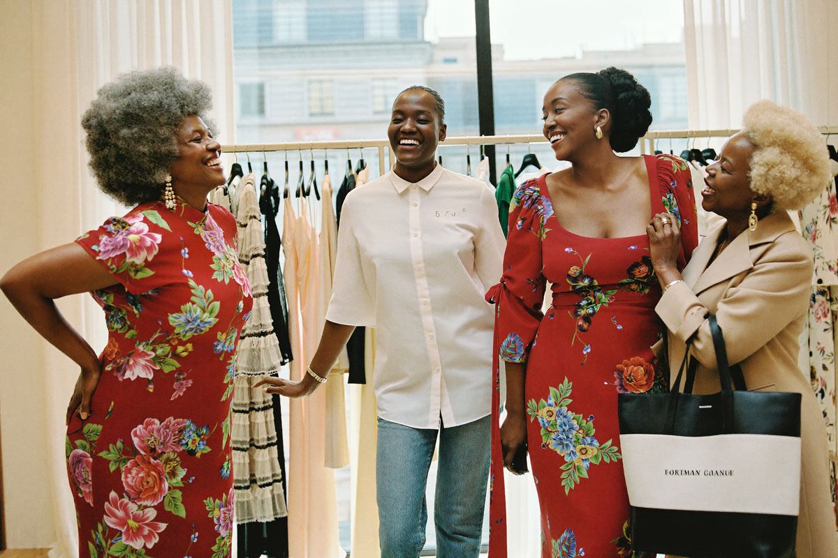 Three customers laughing between the dress rails